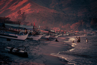 People at beach against sky during sunset