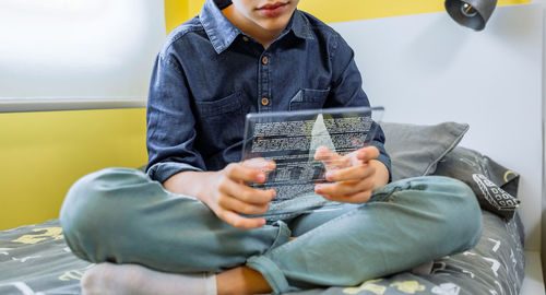 Midsection of woman using mobile phone while sitting on sofa at home