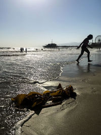 Man walking on beach against clear sky