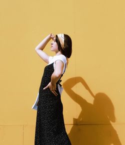 Side view of woman standing against wall
