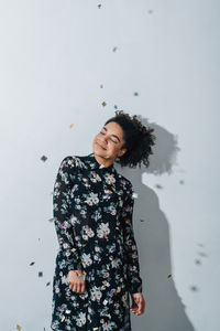 Portrait of young woman standing against white background