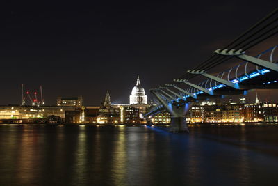 Illuminated city by river at night