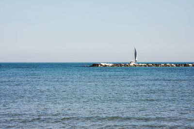 Sailboat sailing on sea against clear sky
