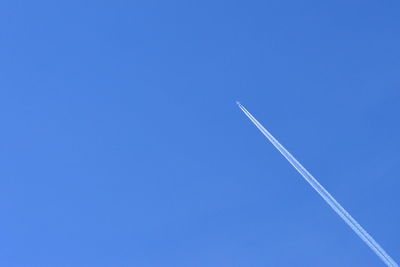 Low angle view of vapor trail against clear blue sky