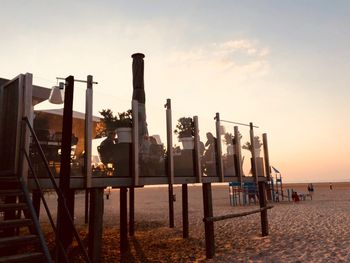 Wooden posts on beach against sky during sunset