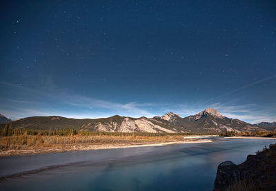 Scenic view of lake and mountains against sky at night