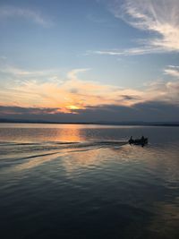 Silhouette person on sea against sky during sunset