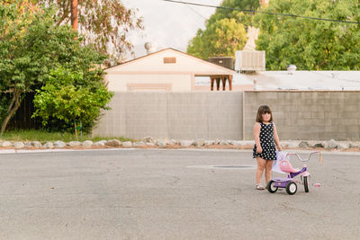 Girl standing by tricycle on road