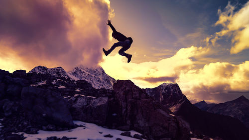 Low angle view of man jumping against mountain during sunset