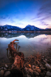 Scenic view of lake by snowcapped mountains against sky