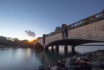 Bridge over river against sky during sunset