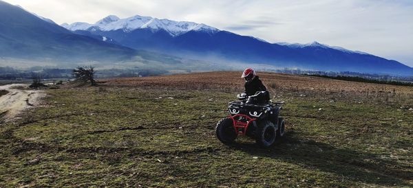 Man riding motorcycle on field against sky