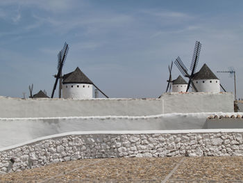 Traditional windmill by building against sky