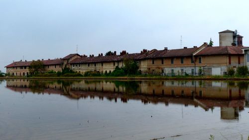 Reflection of buildings on lake against clear sky