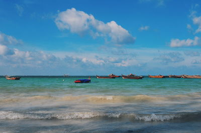 View of boats in sea against cloudy sky