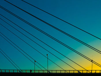 View of suspension bridge cables against sky at sunset
