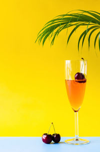 A glass of sparkling rose wine with cherry fruit inside with coconut leaf. summer drink concept.