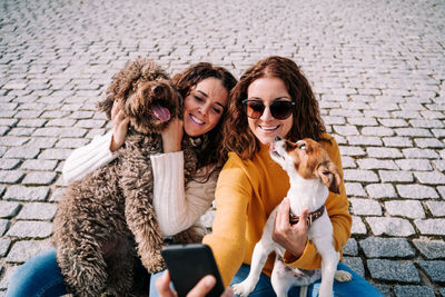 Portrait of happy women with dog sitting outdoors