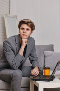 Man with hand on chin sitting on sofa