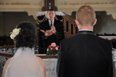 Couple standing in front of priest during wedding ceremony at church