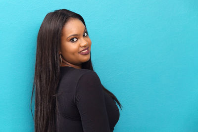 Portrait of young woman against blue background