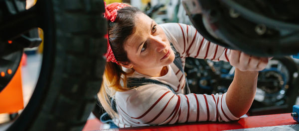 Mechanic woman checking motorcycle on factory