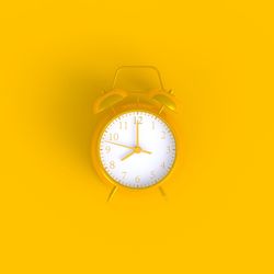 Close-up of clock against yellow background