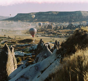 Hot air balloons flying above landscape and rocky mountains