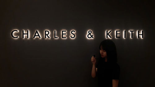 Full length of woman standing against illuminated wall