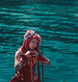 Portrait of smiling young woman standing in sea