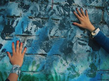 Low section of woman touching water against wall