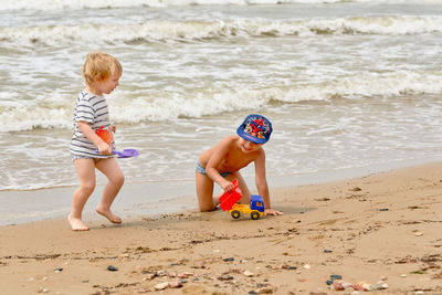 Full length of boy playing with sand at beach