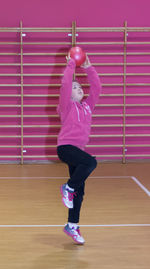 Full length of girl throwing ball at basketball court