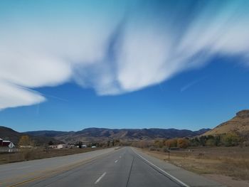 Empty road along landscape against sky