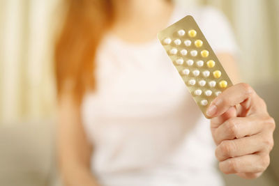 Midsection of woman holding blister pack