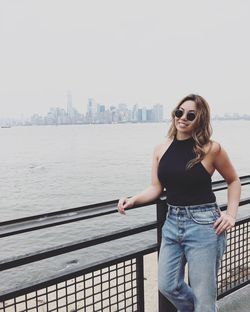 Smiling woman standing by railing against river in city