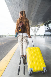 Full length of man holding yellow umbrella on road