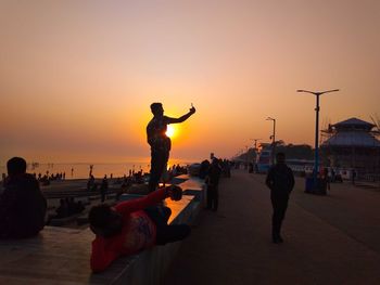 People on beach against sky during sunset