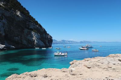 Sailboats on sea against clear blue sky