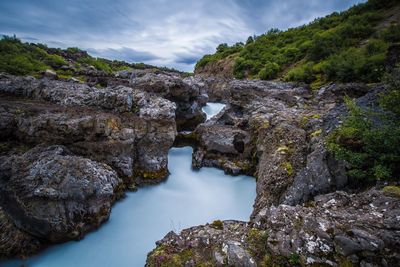 Scenic view of waterfall against sky