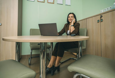 Smiling businesswoman using phone in office. small business talking on phone and smiling, laptop
