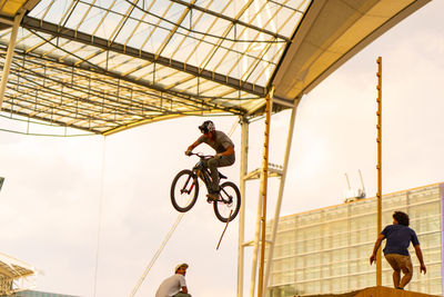 Low angle view of men with bicycle against sky