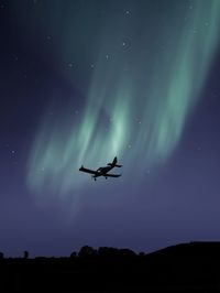 Low angle view of silhouette airplane against sky at night