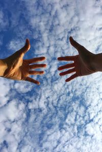 Close-up of human hand against sky during winter