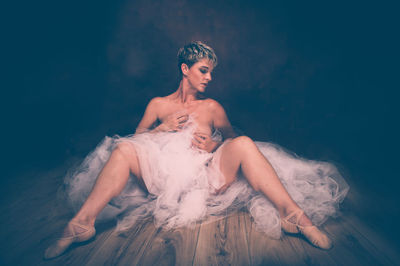 Semi-naked woman wearing tulle tutu against black background