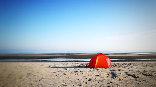 Red umbrella on beach against clear sky
