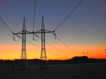 Electricity pylon against sky at sunset