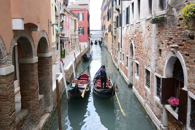 Boats in canal amidst city against sky