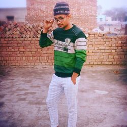 Full length of young man standing against brick wall