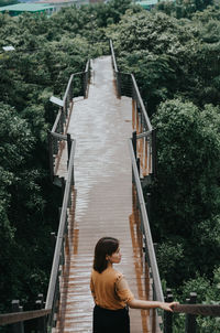 High angle view of woman walking on footbridge by trees